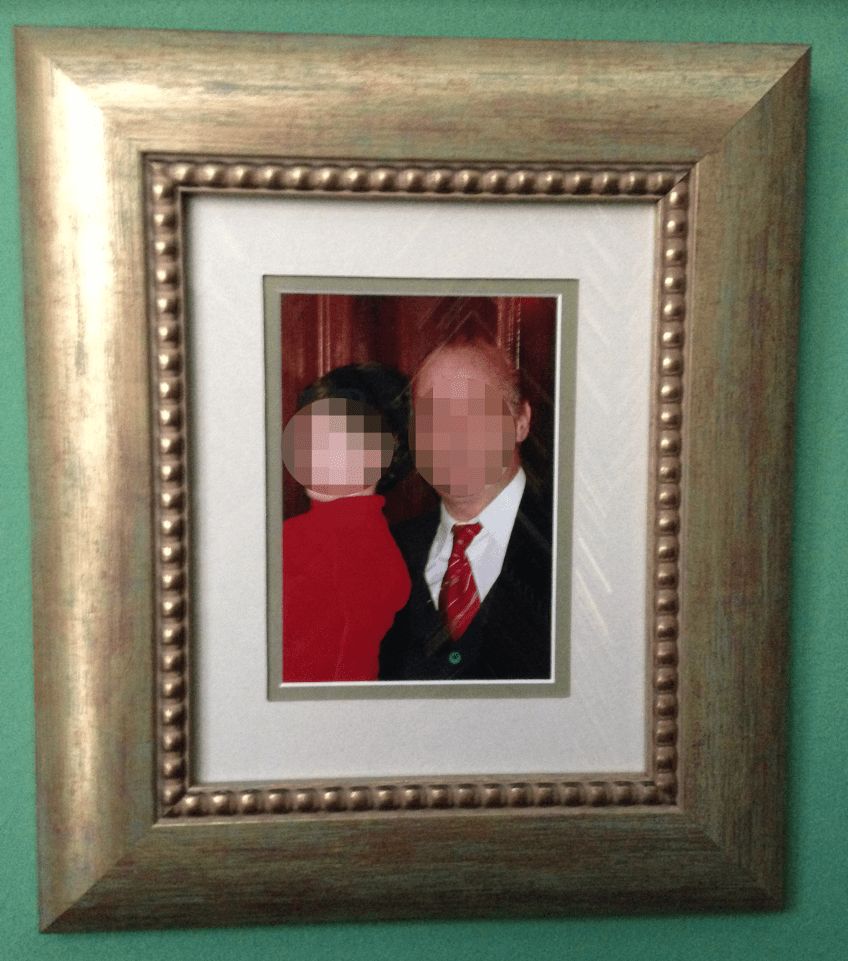 Ξύλινη, φαρδιά, χρυσή κορνίζα με λαδί απόχρωση και σφαιρικά σκαλίσματα στην πατούρα σε γυαλιστερό τζάμι και διπλό εκρού πιτσιλωτό πασπαρτού και λαδί για περίγραμμα.